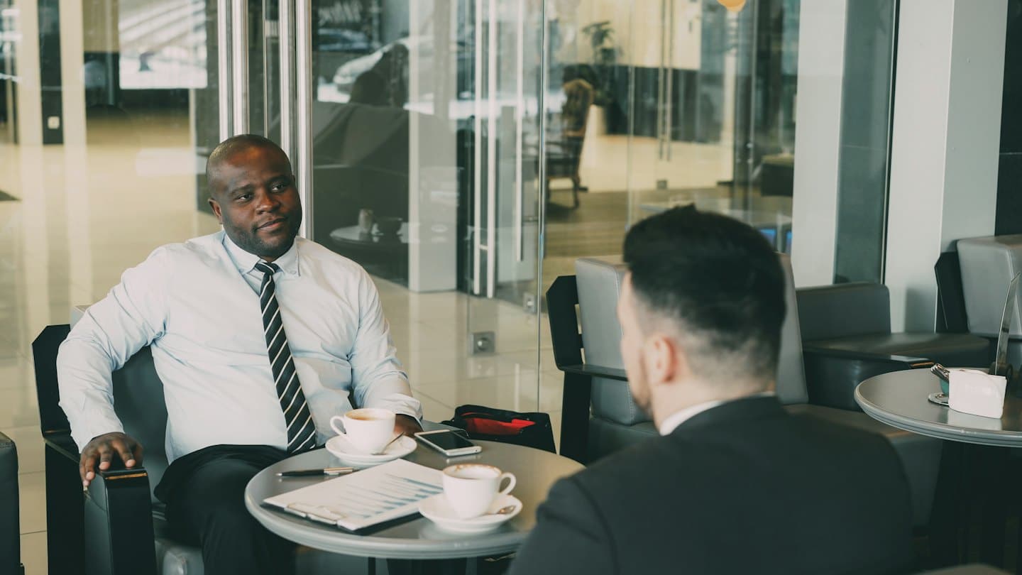 Two businessmen discussing documents at a round table.